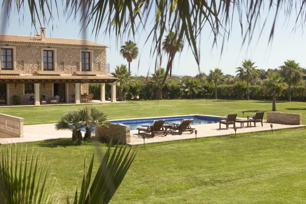 Stone residence with a swimming pool, lawn and palm trees