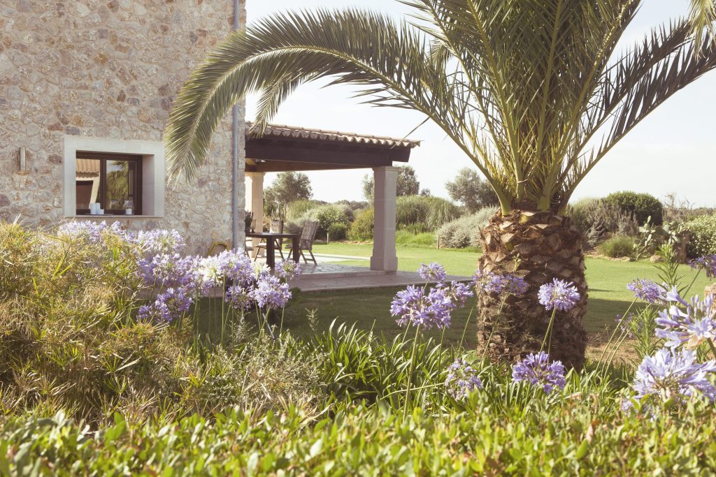 Garden and covered terrace beside a stone residence