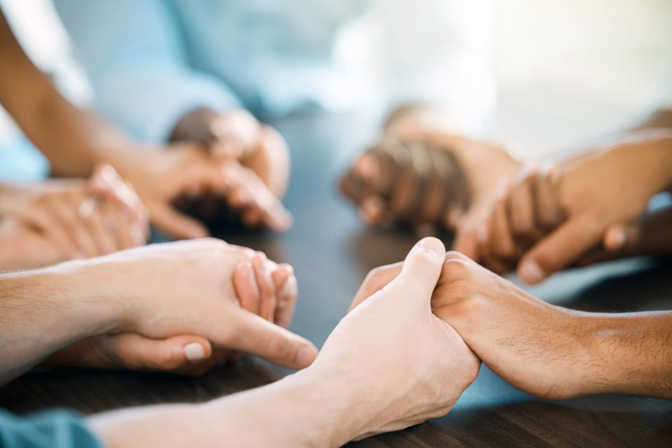 Close-up overhead shot of diverse people holding hands in a circle, symbolizing unity and support