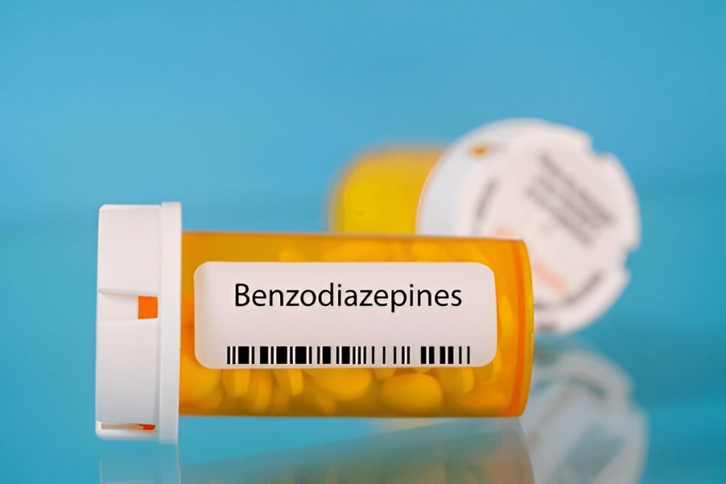 Prescription bottle labeled Benzodiazepines with pills inside on a blue background
