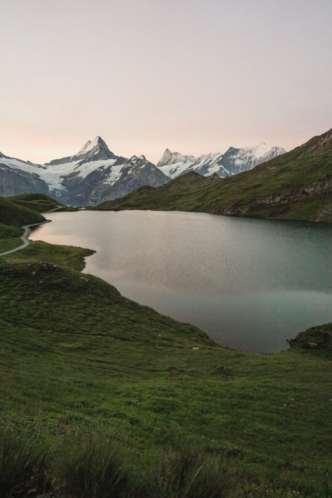 Alpine reservoir surrounded by grassy slopes and mountains