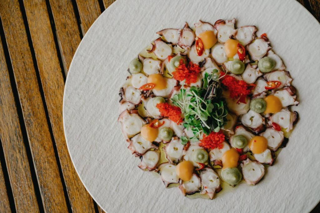 Sliced octopus with vegetables and herbs on a plate