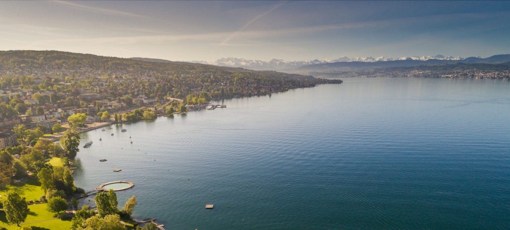 Aerial view of Zurich by Lake Zurich with shoreline neighborhoods and distant snow-capped Alps