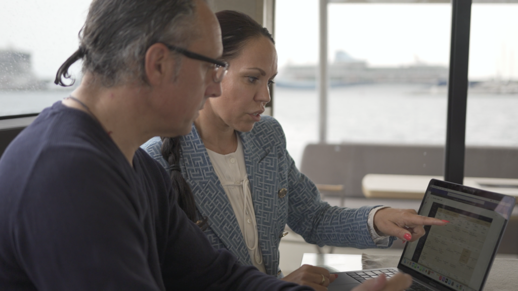 Colleagues reviewing a schedule on a laptop during a meeting by the window